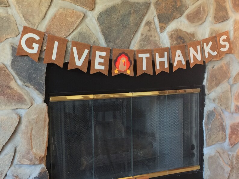 May include: A brown felt banner with white letters that reads "GIVE THANKS" with a brown felt turkey in the middle.