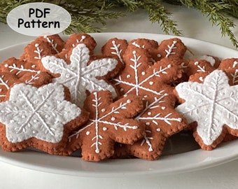 May include: A plate of felt gingerbread snowflake ornaments. The snowflakes are brown with white embroidery and some are white with brown embroidery.