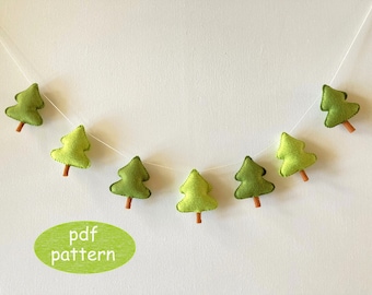 May include: A garland of seven felt green trees with brown stems, strung on white thread. The garland is hanging on a white wall. The text "pdf pattern" is written in white on a green oval.