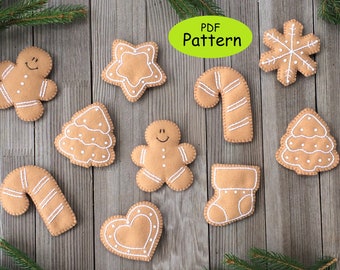 May include: A set of 10 felt Christmas ornaments in the shape of gingerbread cookies, including a star, a candy cane, a stocking, a heart, a gingerbread man, and a snowflake. The ornaments are brown with white stitching and are arranged on a wooden background. PDF Pattern.