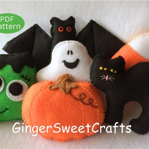 May include: A collection of felt Halloween ornaments including a green monster, a black bat with orange eyes, a white ghost, an orange pumpkin, a black cat, and a piece of candy corn. The image includes the text PDF Pattern and GingerSweetCrafts.
