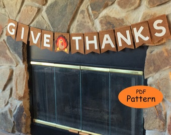 May include: A brown felt banner with white letters that reads "GIVE THANKS" with a felt turkey applique in the middle. The banner is hanging above a fireplace.