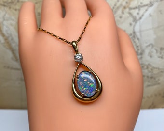 May include: A gold chain necklace with a teardrop-shaped pendant featuring a blue opal gemstone surrounded by a gold frame and a small diamond accent.