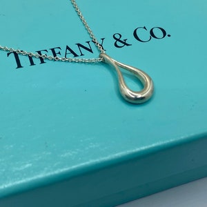 Puede incluir: Un collar de plata Tiffany & Co. con un colgante en forma de lágrima.