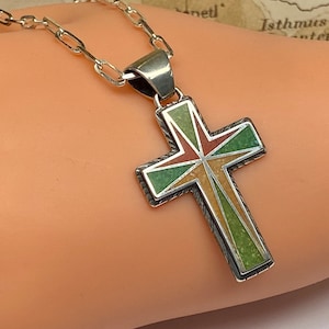 May include: A silver chain necklace with a silver cross pendant. The cross is inlaid with green, brown, and red stones.