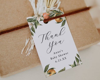 Puede incluir: Una etiqueta de agradecimiento blanca con un borde floral de flores de azahar y hojas verdes. El texto dice "Gracias" en escritura cursiva, seguido de "Baby Shower de Anna 6.23.XX".