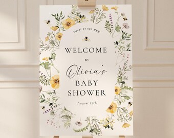 May include: Welcome to Olivia's Baby Shower sign with a floral wreath design featuring yellow flowers, green leaves, and bees. The text reads "Sweet as can BEE, Welcome to Olivia's Baby Shower, August 12th."