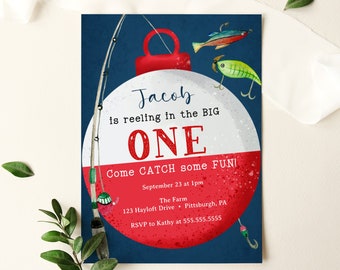 Può includere: Un invito di compleanno a forma di galleggiante da pesca blu e rosso per il primo compleanno di un bambino. L'invito dice "Jacob is reeling in the BIG ONE. Come CATCH some FUN!" con i dettagli della festa, tra cui la data, l'ora, il luogo e le informazioni RSVP.