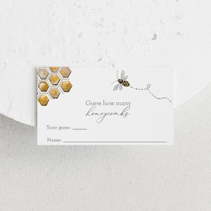 May include: A white card with a bee illustration and a honeycomb pattern. The card says "Guess how many honeycombs" and has a space for a name and guess.