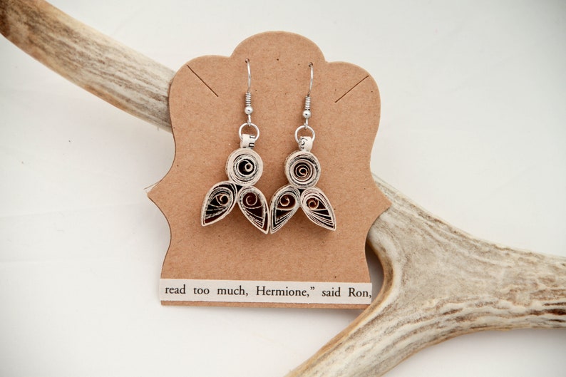 May include: A pair of dangle earrings made from coiled paper strips in shades of cream, brown, and black, attached to silver-toned metal hooks. The earrings are displayed on a tan card with the printed text, read too much, Hermione, said Ron.