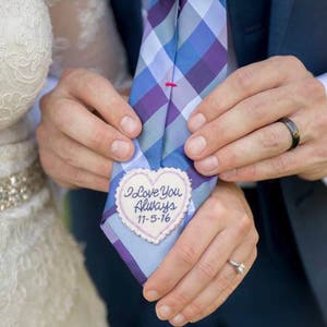 Könnte beinhalten: Eine blaue und violette karierte Krawatte mit einem weißen herzförmigen Patch, auf dem "I love you always 11-5-16" gestickt ist.
