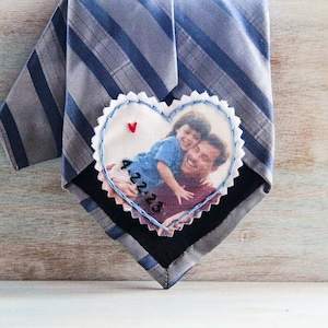 May include: A heart-shaped fabric patch with a photo of a father and child. The patch is sewn onto a striped tie. The date "4.22.13" is embroidered on the patch.