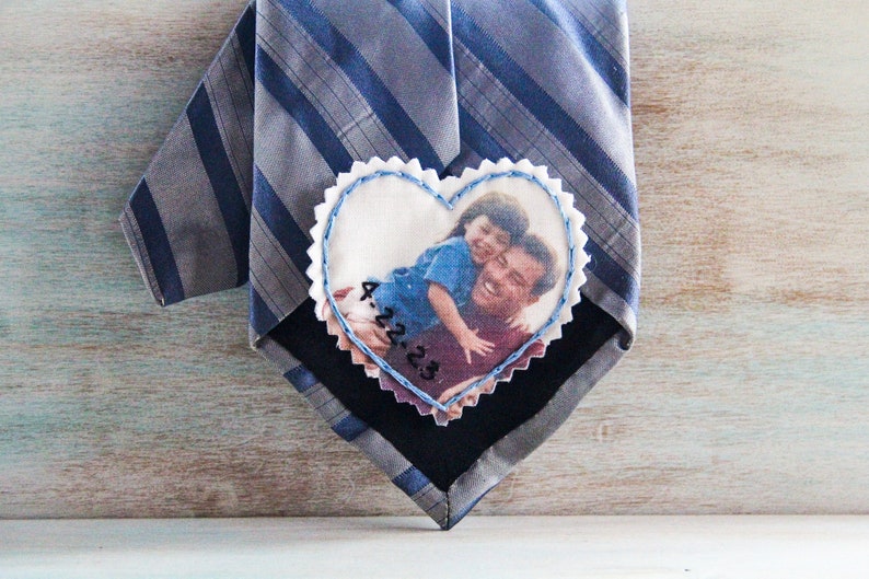 May include: A heart-shaped fabric patch with a photo of a father and child. The patch is attached to a striped tie. The date "4.22.23" is embroidered on the patch.