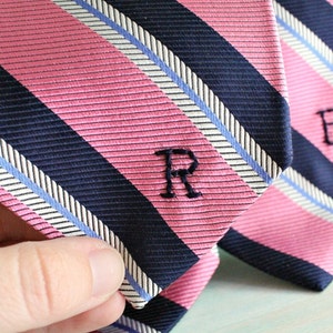 May include: Two pink and navy striped ties with embroidered initials, "R" and "B", on the front.