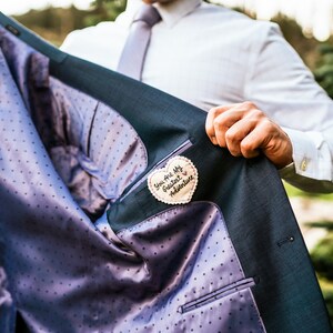 Könnte beinhalten: Ein blauer Anzugjackett mit einem weißen Polka-Dot-Futter. Ein herzförmiger Stoff-Patch ist an der Innenseite des Jacketts angenäht, auf dem der Text "You are my greatest adventure" gestickt ist.