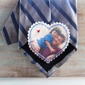 May include: A heart-shaped fabric patch with a photo of a father and daughter. The patch is attached to a striped tie.