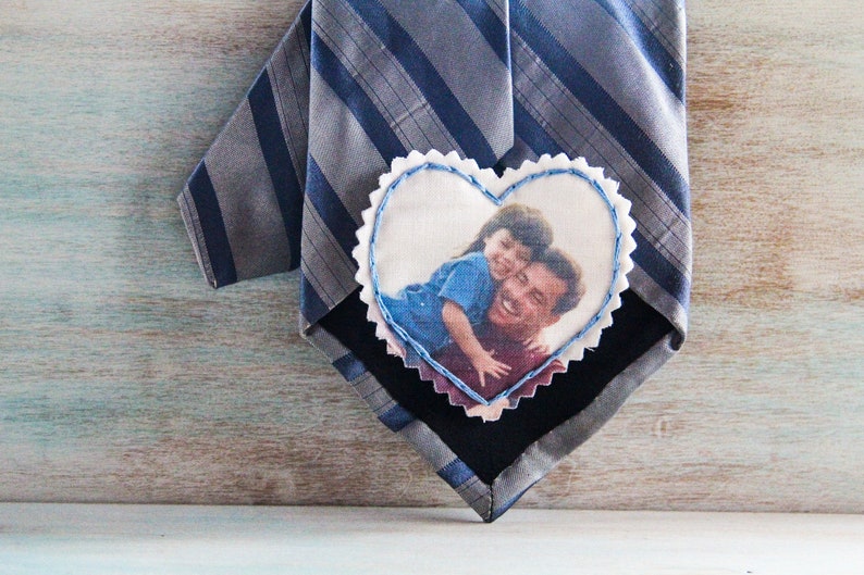 May include: A gray and blue striped tie with a heart-shaped fabric patch sewn on. The patch has a photo of a father and child smiling.