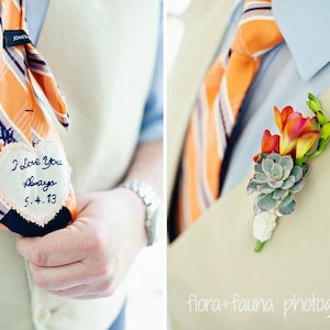 May include: A groom's tie with a heart-shaped patch that says "I love you always 5.4.13". The groom is also wearing a buttonhole with orange flowers and a succulent.