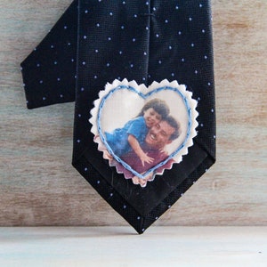 May include: A black tie with a white heart-shaped patch sewn on. The patch has a photo of a father and child printed on it.