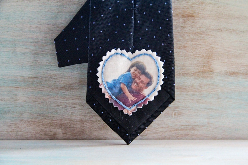 May include: A black tie with a white heart-shaped patch sewn on. The patch has a photo of a father and child printed on it.