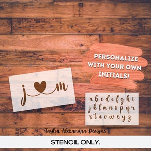 May include: A white stencil with the letters "j" and "m" connected by a heart. The letters are in a cursive font. The stencil also includes a full alphabet in cursive font. The text "PERSONALIZE WITH YOUR OWN INITIALS!" and "STENCIL ONLY." is also included in the image.