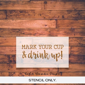 May include: A stencil on a wood background with the text "MARK YOUR CUP & drink up!" and the text "Taylor Alexandra Designs STENCIL ONLY."