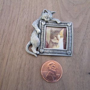 KAT HOLDING A PICTURE Frame Pin-  looking at the picture in the frame - It is 2&quot; high x 1 58 &quot; wide - has a heart in each corner - Pewter