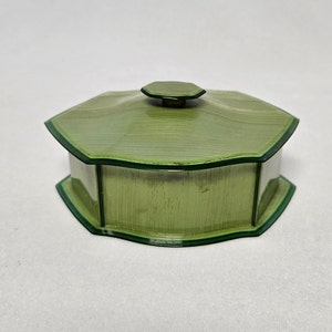 May include: A green octagonal trinket box with a lid. The box has a green and white striped pattern and a dark green trim.