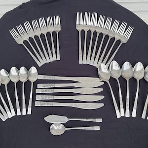 May include: A set of silverware in a silver finish. The set includes forks, spoons, and knives. The silverware has a decorative pattern on the handles.