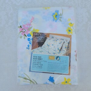 May include: A white flat sheet with a floral pattern in shades of blue, pink, yellow, and green. The sheet is labelled "Misty Garden Perma-Prest Muslin Sheet" and is full size, measuring 81 inches by 96 inches. The sheet is made of 50% polyester and 50% cotton.
