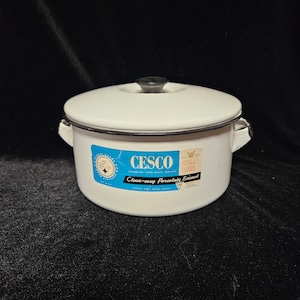 May include: White enamel CESCO pot with a black handle and rim. The pot has two side handles and a lid. A blue and white label on the front reads "CESCO Clean-easy Porcelain Enamel."
