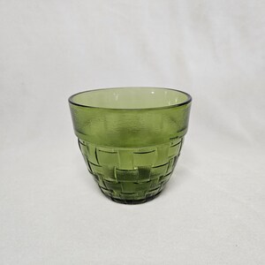 May include: A green glass drinking glass with a woven pattern.