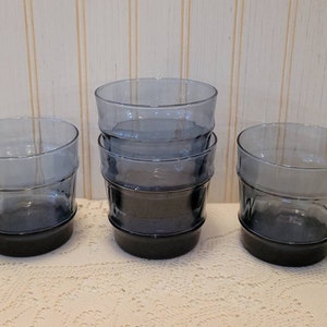 Può includere: Set di sei bicchieri in vetro blu con un design testurizzato. I bicchieri hanno una base blu scuro e una parte superiore blu più chiara.