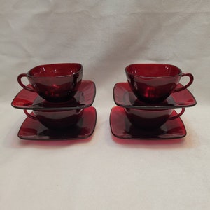 May include: Set of two red glass teacups and saucers. Each cup and saucer is stacked on top of another cup and saucer.