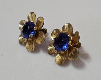Könnte beinhalten: Ein Paar goldfarbene Ohrringe in Blumenform mit blauen Strasssteinen in der Mitte.