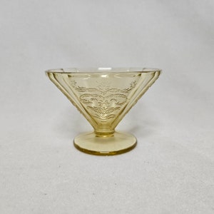 May include: A small, clear, yellow glass dessert dish with a scalloped rim and a delicate etched floral design.
