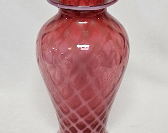Pode incluir: Um vaso de vidro cor de cranberry com um padrão de diamante. O vaso tem uma borda larga e alargada e um corpo arredondado que se estreita para uma base estreita. O vidro tem um acabamento brilhante e é translúcido.
