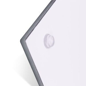 Pode incluir: Close-up de um sinal retangular branco com um adesivo redondo transparente na esquina.