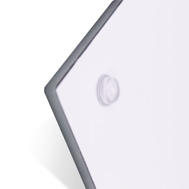 Pode incluir: Close-up de um sinal retangular branco com um adesivo redondo transparente na esquina.