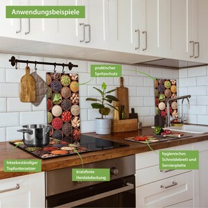 Pode incluir: Uma cozinha com arm&aacute;rios brancos e um fog&atilde;o preto. H&aacute; tr&ecirc;s pain&eacute;is de vidro com um design de especiarias na parede. Os pain&eacute;is s&atilde;o etiquetados como "praktischer Spritzschutz", "hitzebest&auml;ndiger Topfuntersetzer" e "kratzfeste Herdabdeckung". H&aacute; tamb&eacute;m uma t&aacute;bua de cortar etiquetada como "hygienisches Schneidebrett und Servierplatte".