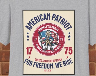 May include: A grey t-shirt with a vintage-style graphic design featuring a cartoon illustration of a man holding an American flag. The graphic includes the text "American Patriot", "Minutemen", "Continental Army", "1775", "United States of America", "For Freedom, We Rise", and "Est. 1775".
