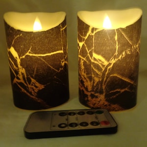 以下が含まれることがあります： ちらつく炎の効果のある、黒と金の模様の大理石の円柱形のろうそくが2本。ろうそくは電池式で、リモコンが付属しています。