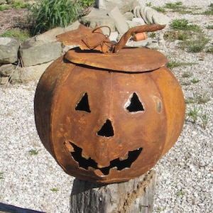 May include: A rusty metal pumpkin with a carved jack-o'-lantern face. The pumpkin is sitting on a wooden post.