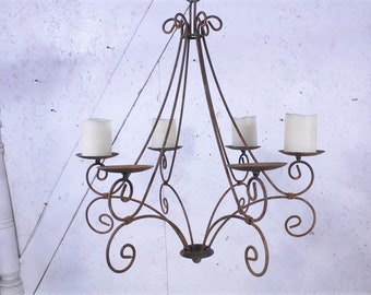 May include: A rustic metal chandelier with five candle holders. The chandelier is made of wrought iron and has a dark brown finish. The candle holders are designed with a simple, elegant scrollwork.