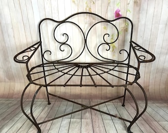 May include: A rusty metal garden bench with a decorative scrolled back and a slatted seat. The bench has a rustic, vintage look.