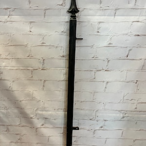 May include: Black metal fence post with a decorative finial on top. The post is about 4 feet tall.
