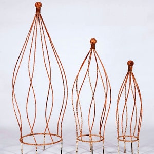 May include: Three rust-colored metal plant cages of varying sizes. The cages are made of thin wire and have a rounded, teardrop shape. The largest cage is about 3 feet tall, the middle cage is about 2 feet tall, and the smallest cage is about 1 foot tall.