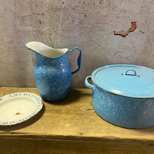 May include: A blue and white enamel pitcher, a blue and white enamel pot with a lid, and a white plate with blue alphabet letters around the edge.