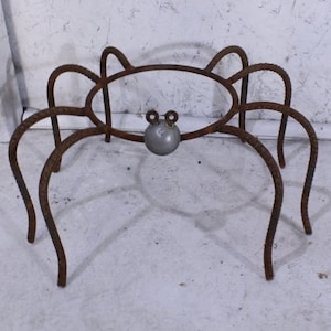 May include: A rusty metal sculpture of a crab with a round body and eight legs. The sculpture is made of rebar and has a rustic, industrial look.