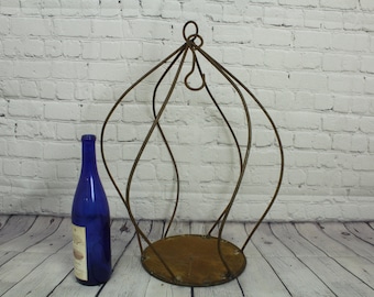 May include: A rusty metal plant stand with a round base and a dome-shaped top. The stand is made of twisted metal and has a rustic look.